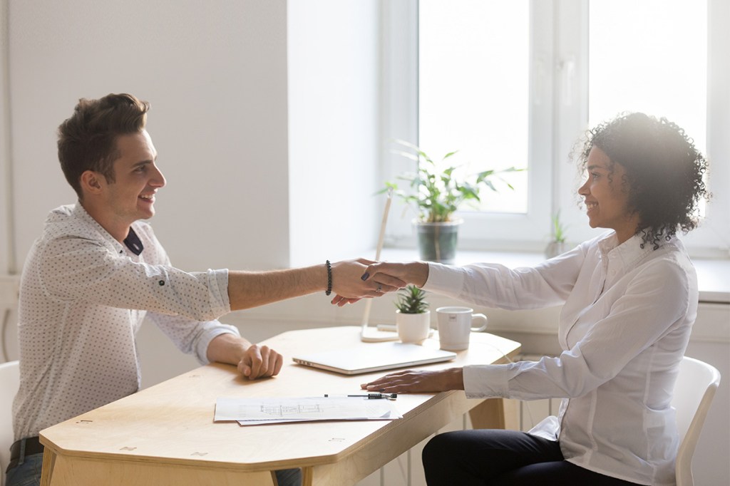 property manager and tenant shaking hands above a lease agreement