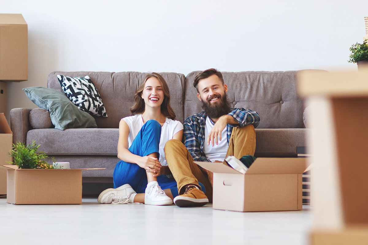 happy tenants in front of a couch with moving boxes