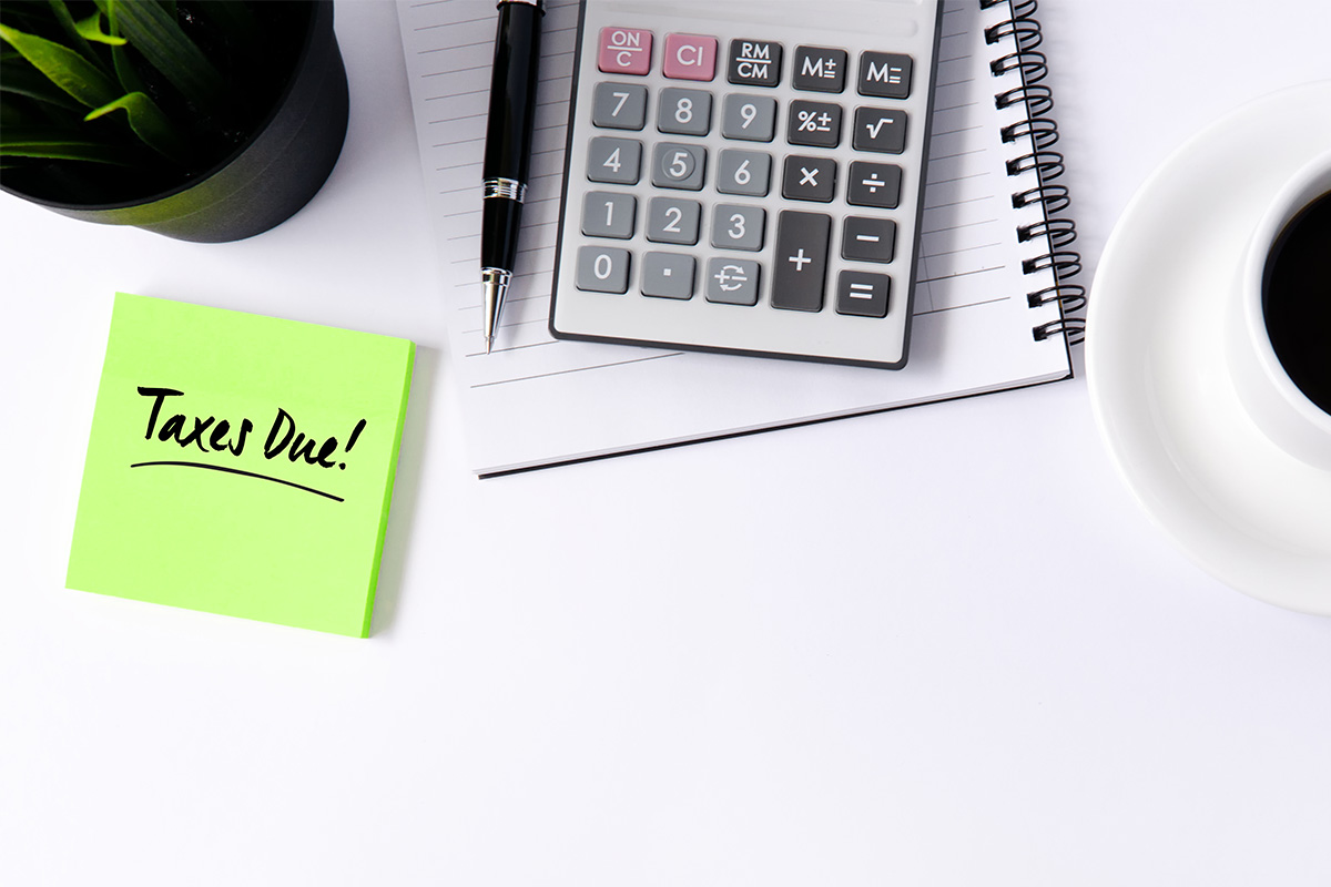 desk with calculator, coffee and taxes due post-it