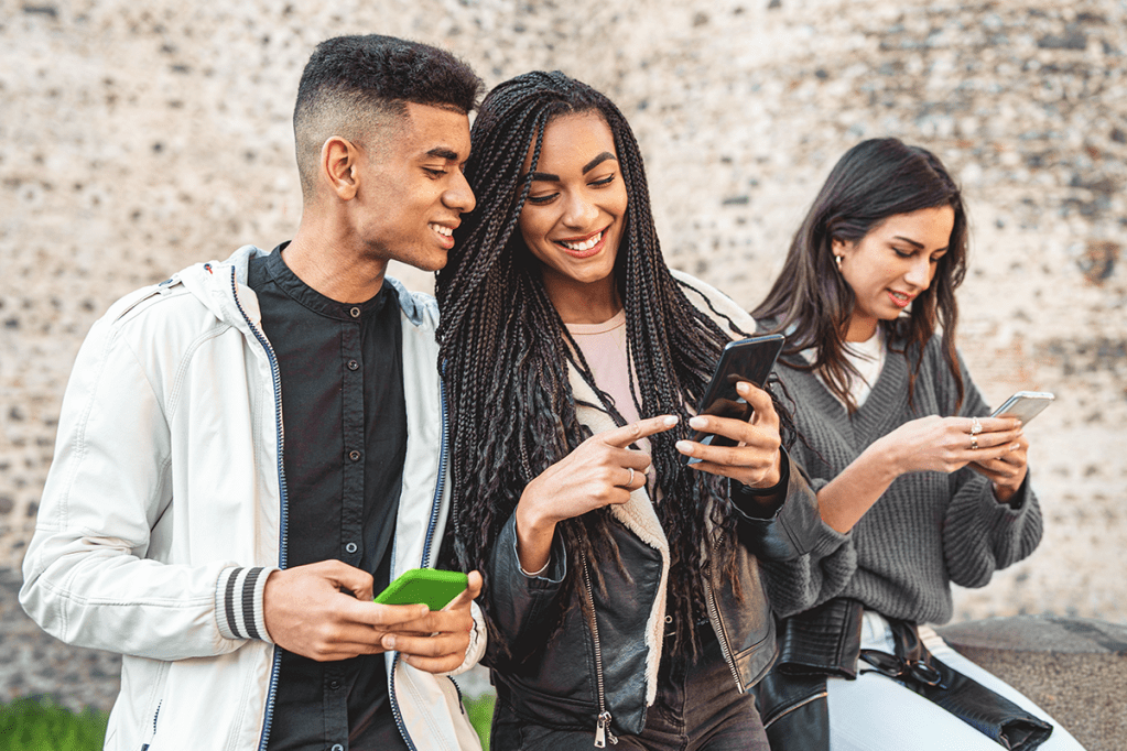 Several young people of Gen Z looking at mobile phones and smiling