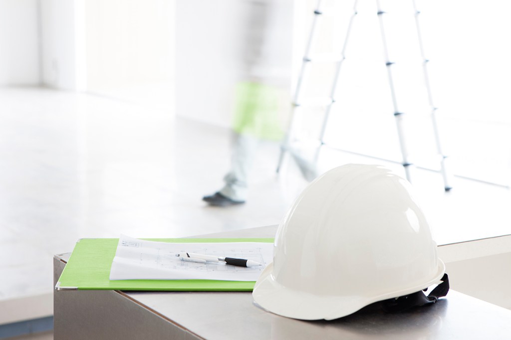 Hard hat and clipboard in commercial setting that is a planned office conversion to multifamily