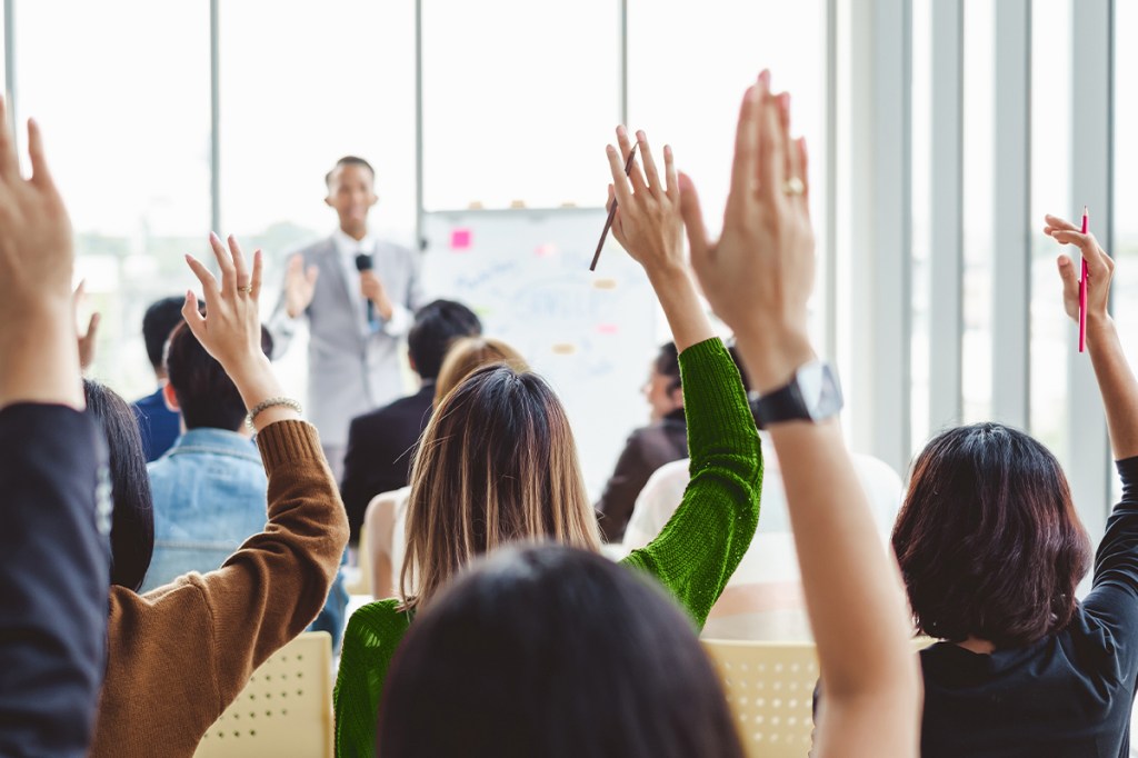 Property managers raising hands to ask a question