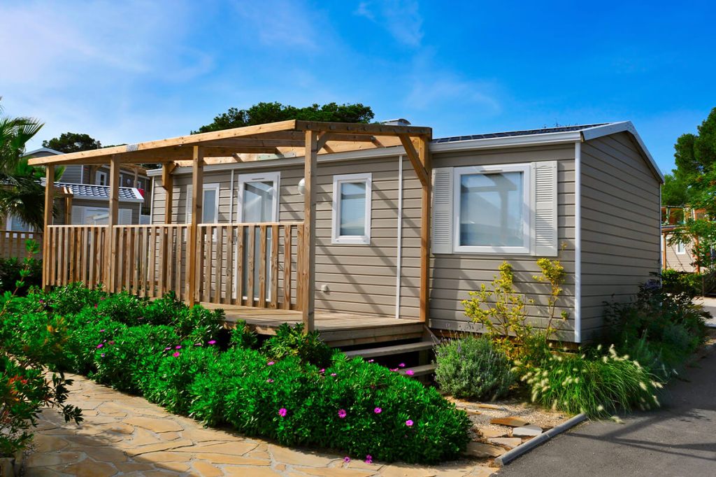 Image of a manufactured home with green bushes in front.