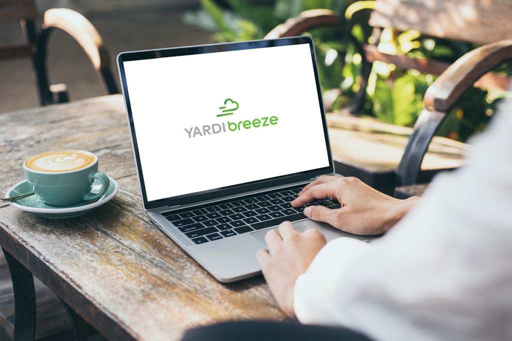Person on laptop showing Yardi Breeze logo, looking for Honest Answers To Common Property Manager Questions