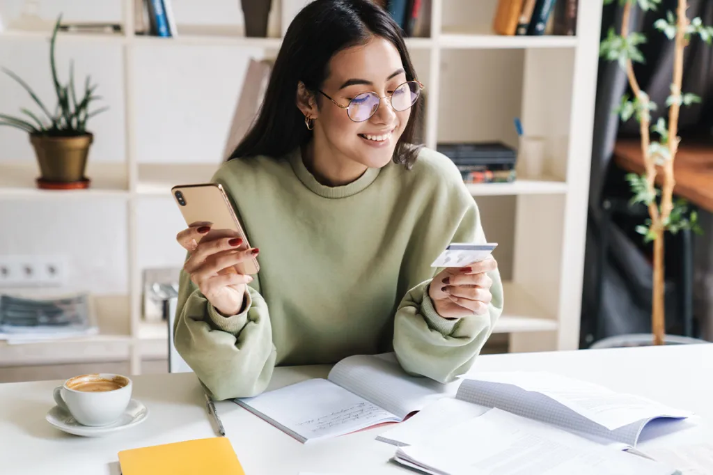 Woman paying bill with phone and credit card in hand