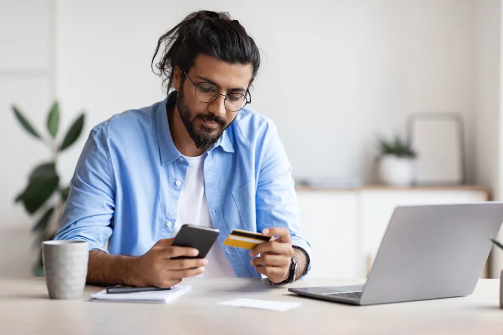 Many looking at his phone with a credit card in hand